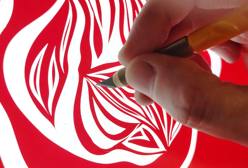 Image of Rubylith red film with the letter E peeled away
